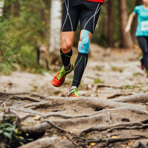 male runner run forest race on knee kinesio tape